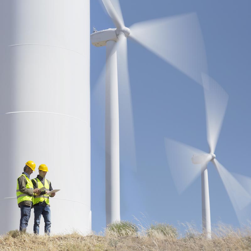 2 men stood underneath a wind turbine