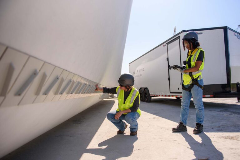 Two technicians inspect blades at a factory