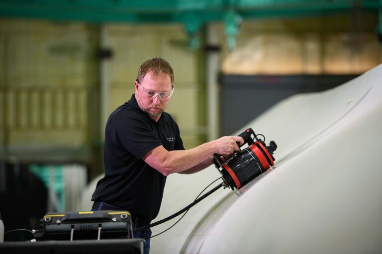 Engineer using Ultrasonic Testing on a wind turbine blade