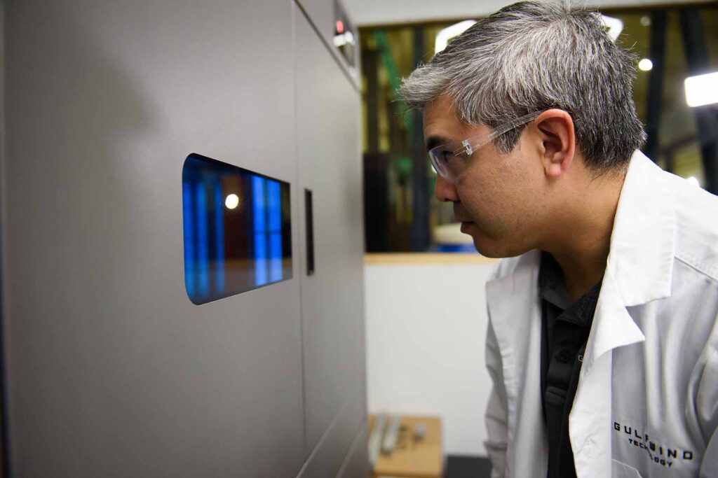 An Engineer looks inside a 3D printing machine