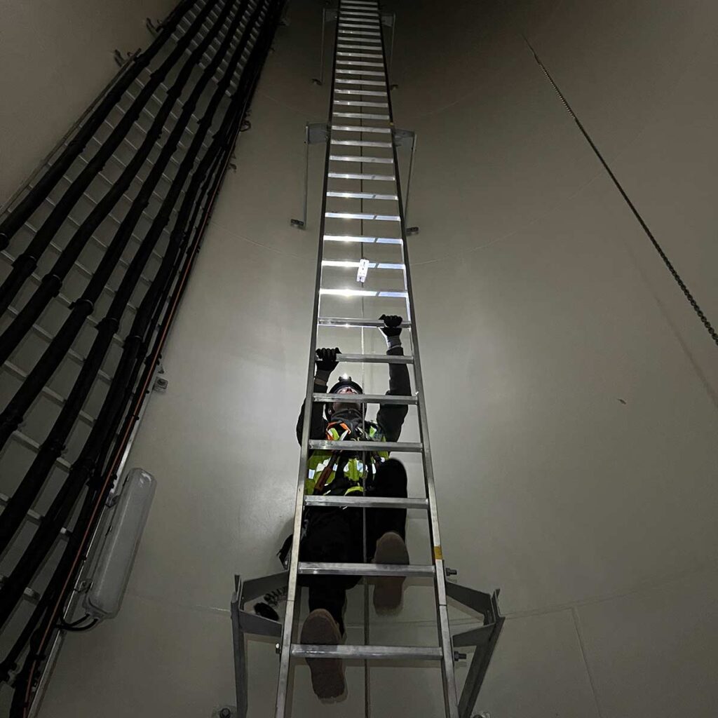 Wind Turbine technician climbing a ladder inside a wind turbine tower